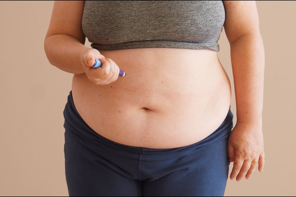 Overweight woman applying diabetes medicine